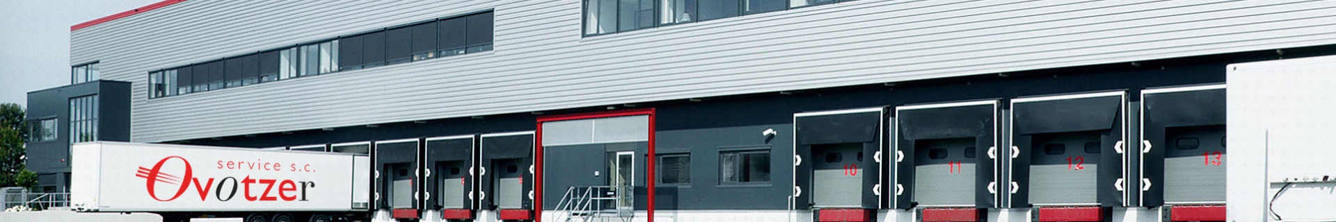 Naczepa chłodnicza z logo Ovotzer Service przy rampach załadunkowych magazynu